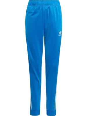 Zdjęcie produktu Jasnoniebieskie spodnie dresowe z ikonicznymi paskami Adidas Originals