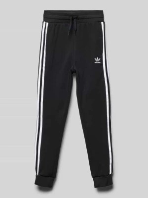 Zdjęcie produktu Spodnie dresowe o kroju regular fit z wyhaftowanym logo model ‘TREFOIL’ adidas Originals